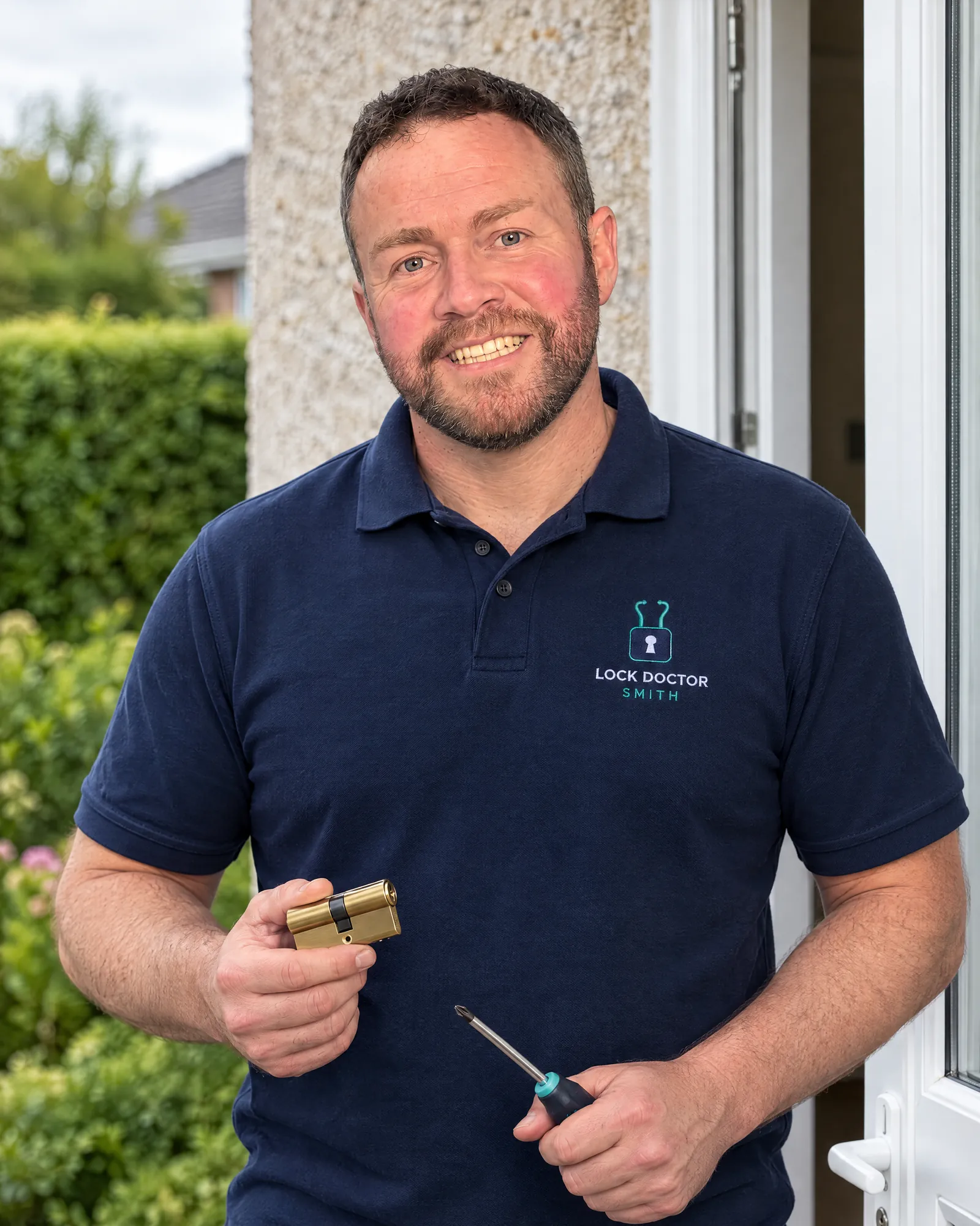 Brian Smith in a Lock Doctor Smith polo shirt at a front door, holding a new cylinder lock and a screwdriver